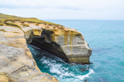 Rock formation in sea against sky