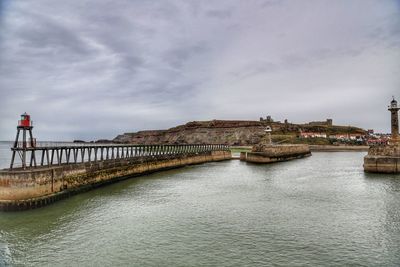 Bridge over river against cloudy sky