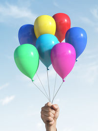 Low angle view of person holding balloons