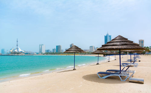 Deck chairs on beach against blue sky