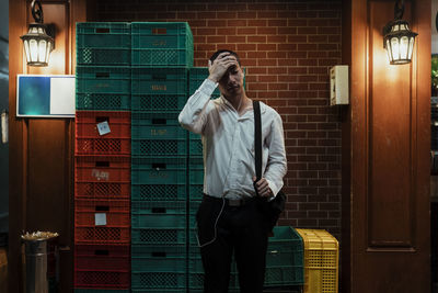 Full length of man standing against brick wall