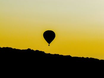 Silhouette hot air balloon against orange sky