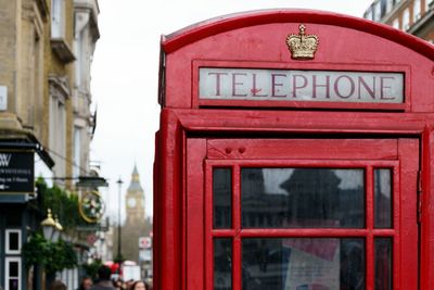 Text on red telephone booth in city