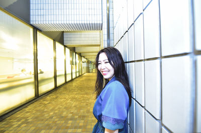 Portrait of smiling young woman standing in corridor