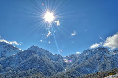 Scenic view of snowcapped mountains against bright sun