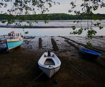 Boat moored on lake against sky