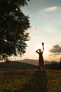 Rear view of woman standing on field against sky