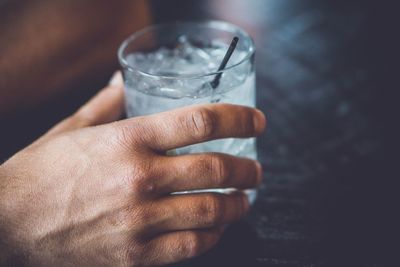 Cropped hand of man holding drink at table