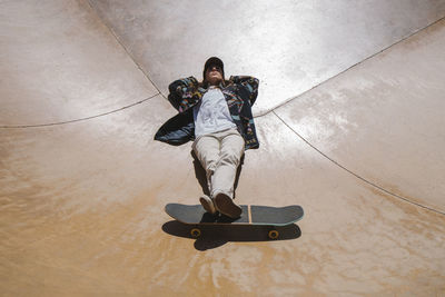 Young woman with hands behind head lying on sports ramp