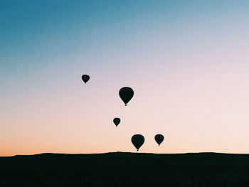 Silhouette hot air balloons against sky during sunset