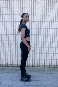 Full length of young woman standing against chainlink fence