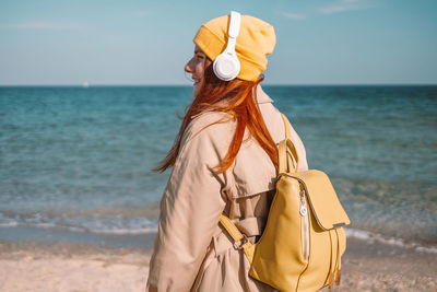 Rear view of woman standing at beach against sky