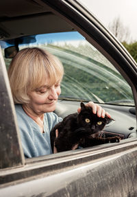 Senior woman with dog sitting in car