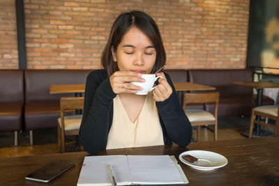 Young woman using mobile phone while sitting on table