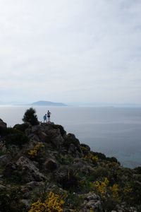 Friends standing on cliff against sea