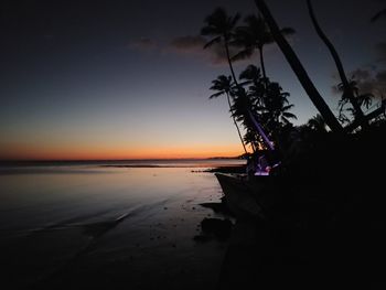 Silhouette trees on beach against sky during sunset