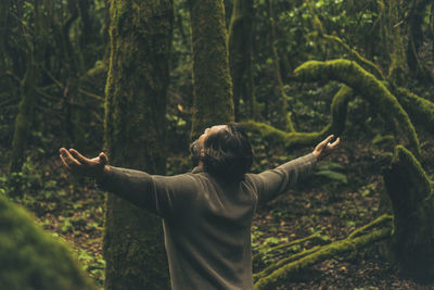 Rear view of woman standing in forest