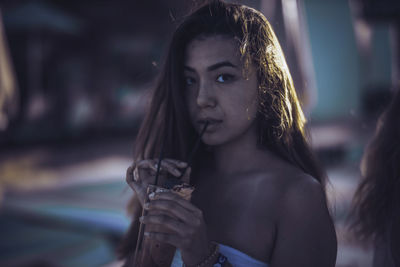 Close-up portrait of young woman having drink while standing outdoors