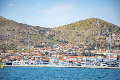 Sailboats in sea by city against sky