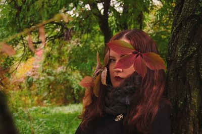 Close-up of young woman standing by tree