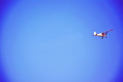 Low angle view of airplane against clear blue sky