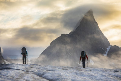 People on snowcapped mountain against sky