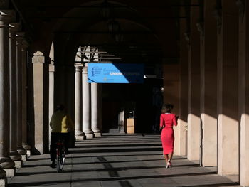 Rear view of woman walking on footpath against building