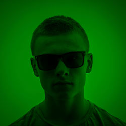 Portrait of man wearing sunglasses against green background