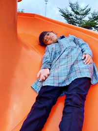 Midsection of boy standing against orange wall