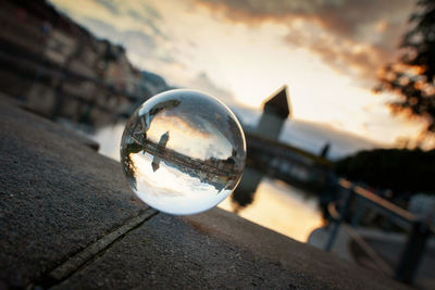 Close-up of crystal ball on glass against sky