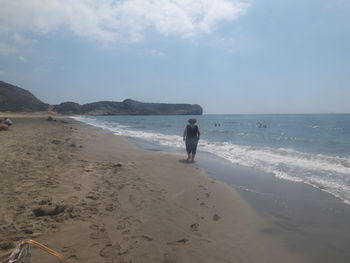 Rear view of man on beach against sky