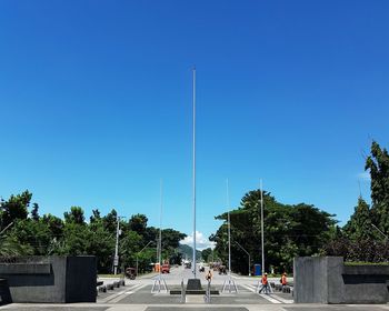 Road and trees against clear blue sky