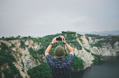 Man photographing on mountains against sky