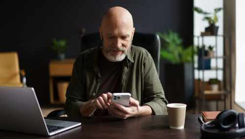 Young woman using mobile phone while sitting on table