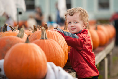 Portrait of boy standing by pumpkins