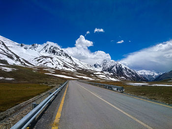 Road by snowcapped mountains against sky