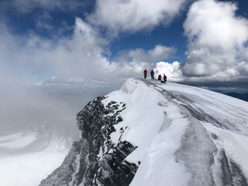 People on snowcapped mountain against sky