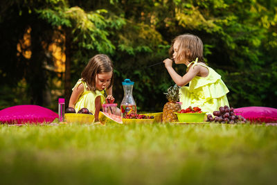 Cute siblings having food and drink in park