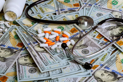 Close-up of medicines and stethoscope on paper currencies