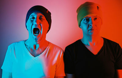 Portrait of two man wearing knit hat against colored background 