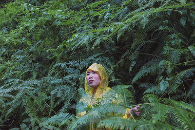 Woman in raincoat standing against plants