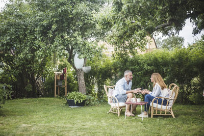 Full length of couple talking while sitting in backyard