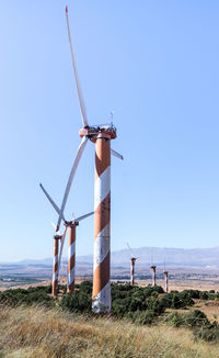 Windmill on field against clear blue sky