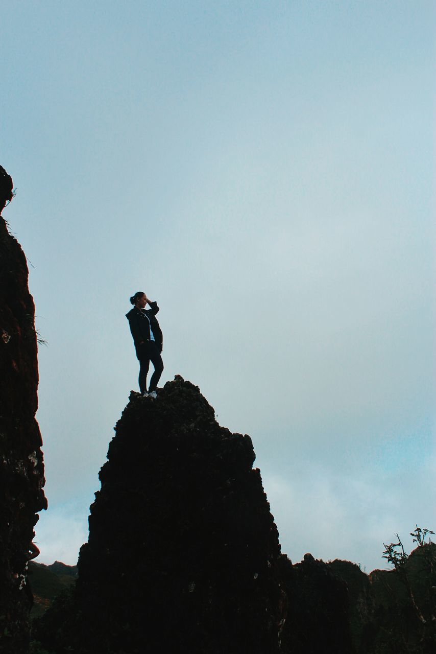 full length, low angle view, adventure, leisure activity, lifestyles, men, day, outdoors, nature, climbing, mountain, real people, sky, risk, clear sky, challenge, one person, young adult, beauty in nature, people