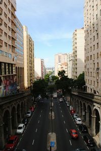 Vehicles on road in city against sky