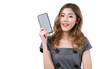 Portrait of young woman using mobile phone against white background