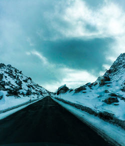 Road amidst snow covered mountains against sky
