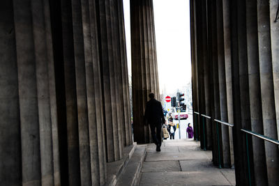 Rear view of man walking on colonnade