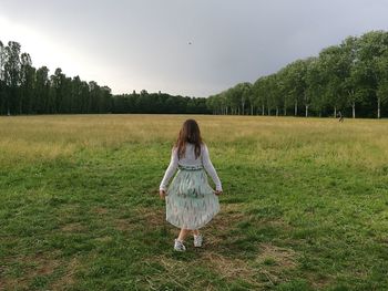 Rear view of woman standing on field against sky