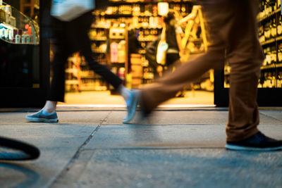 Low section of people walking on street in city